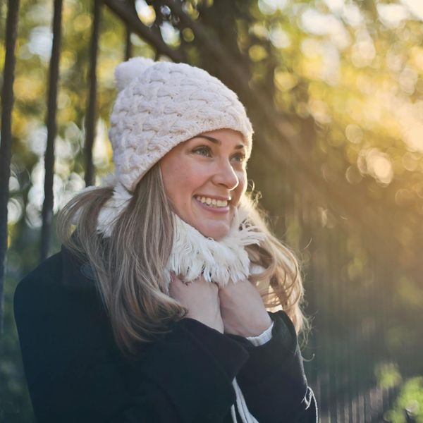 Person smiling and stretching outdoors in a park at sunrise.